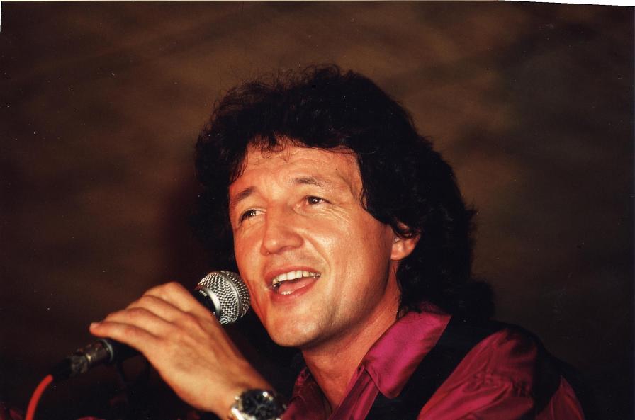 Tony Sampieri chantant sur scène, chemise bordeaux